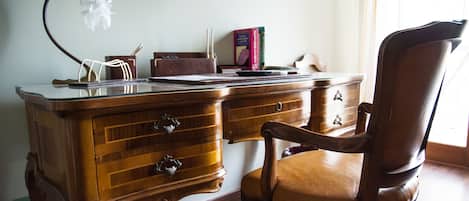 A wooden desk with drawers, a lamp, and a chair.