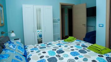Un dormitorio con cama, armario, espejo y televisor en la habitación contigua.