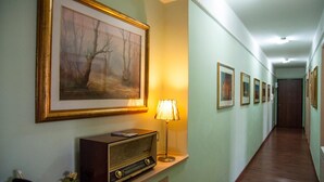 A hallway with framed artwork on the walls, a vintage radio, and a lamp. - Alma B&B (Crotone)