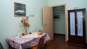 A dining area with a table set for two, a vase with flowers, and a framed picture on the wall. - Alma B&B (Crotone)