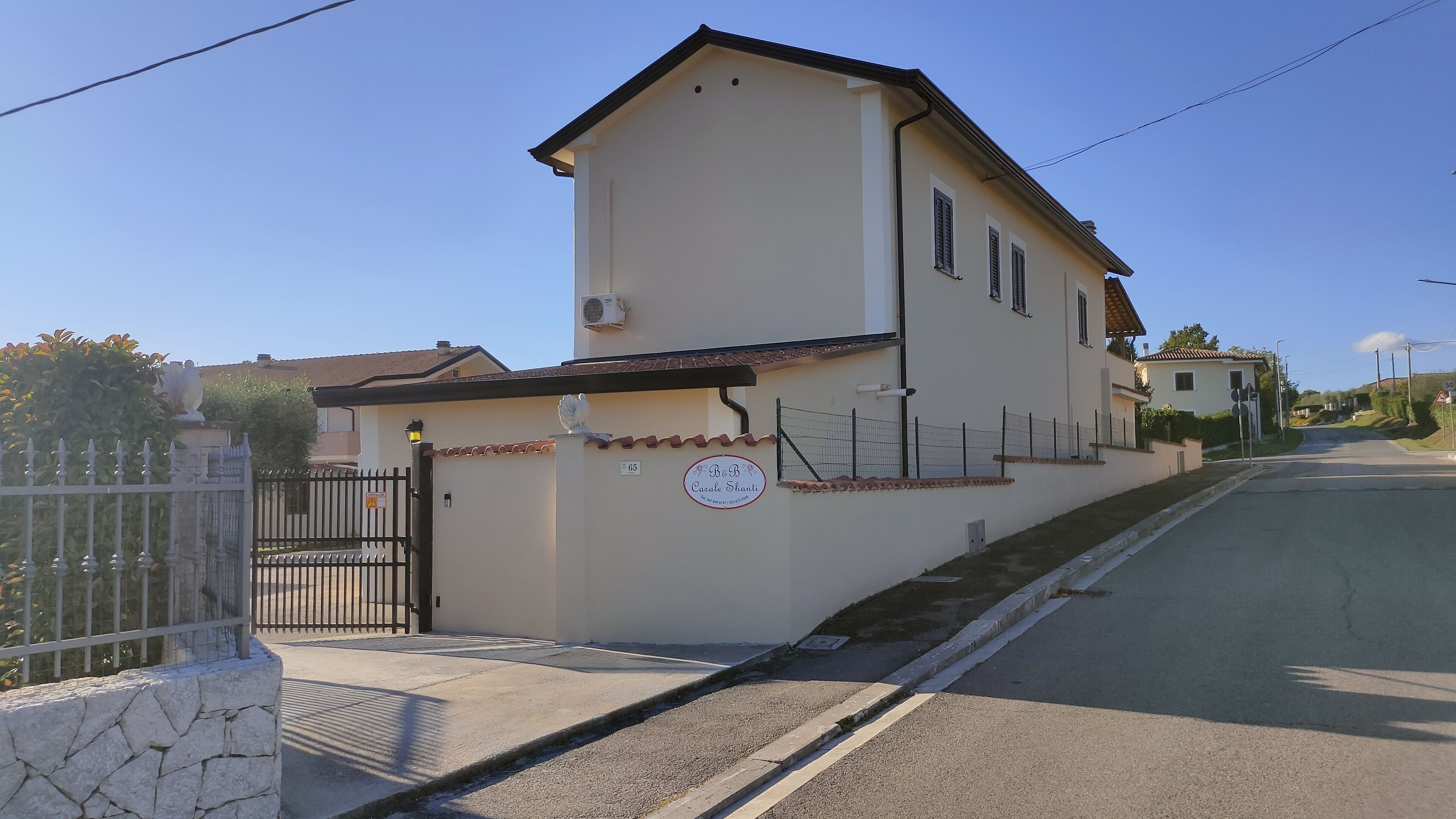 A two-story building with a beige facade, a gated entrance, and a sign indicating a price of 65.