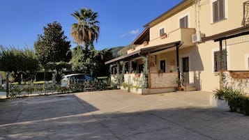 Un edificio residencial con porche cubierto, un coche estacionado al frente y follaje circundante.