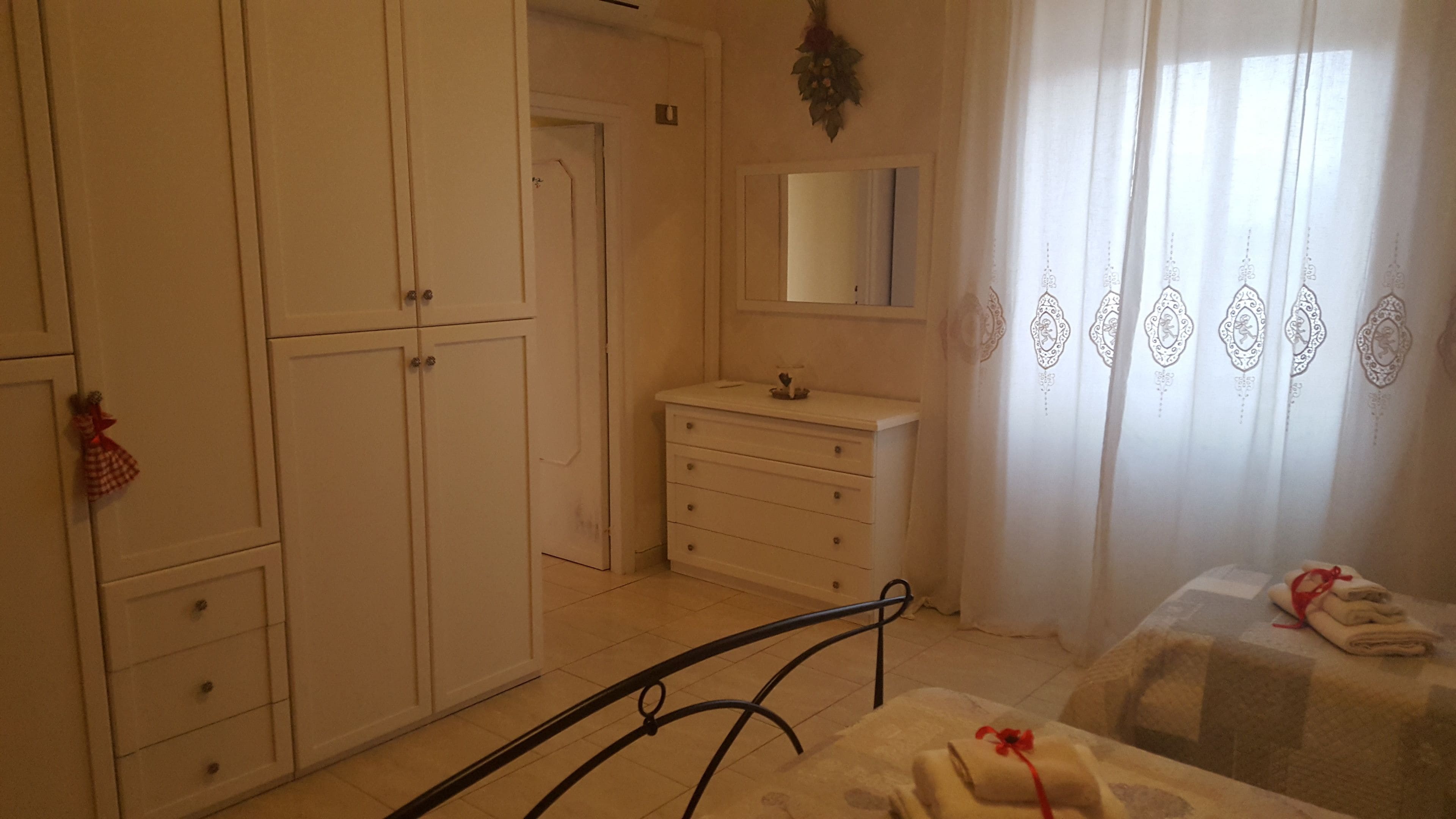 Une chambre à coucher comprenant un lit, une armoire, une commode et une salle de bain avec un miroir.