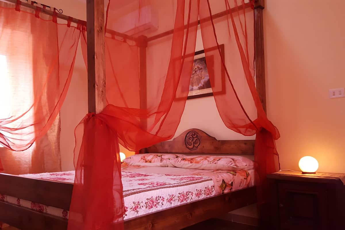 Una cama con dosel adornada con un edredón floral y un cabecero con un símbolo Om.