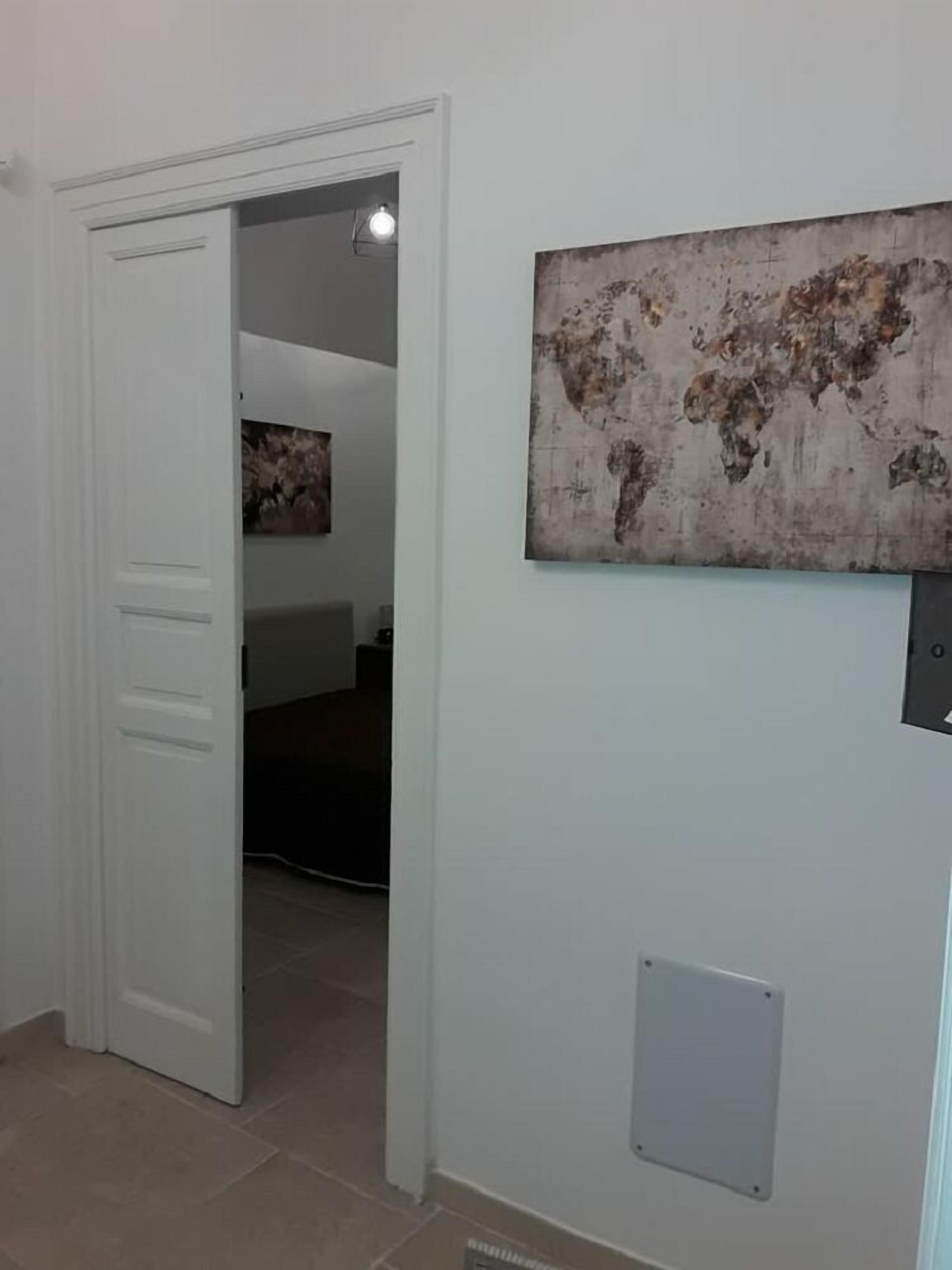 En gang med en hvid dør, et verdenskort som billedkunst på væggen og en ventil.