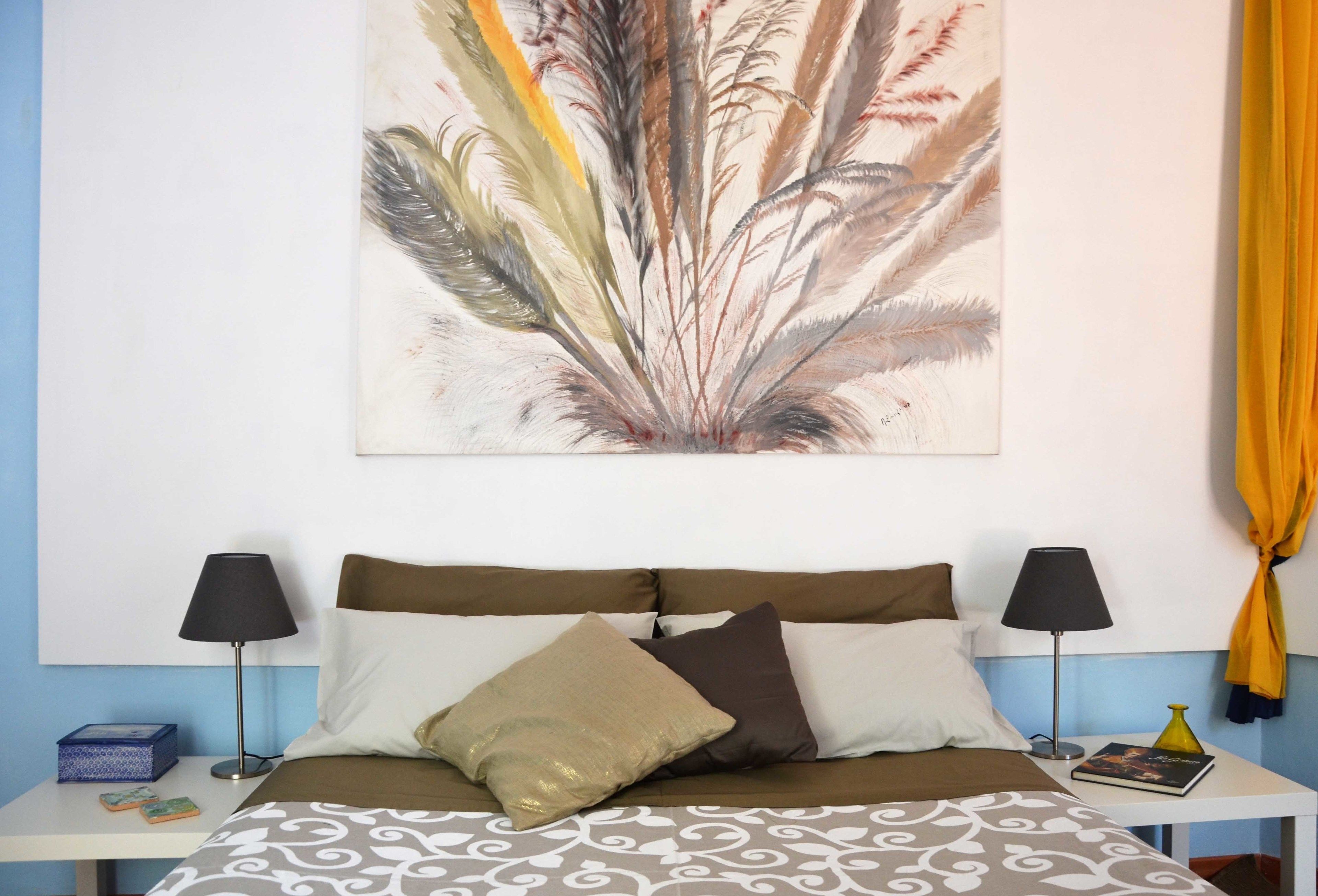 A neatly arranged bedroom with a bed, two bedside tables, a lamp, and a wall-mounted artwork.