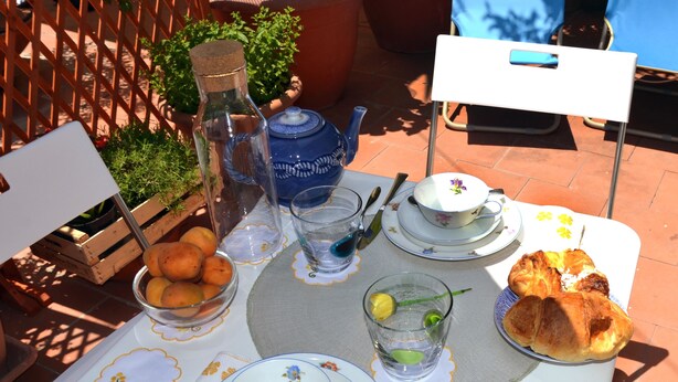 A table set outdoors with a teapot, cups, plates, and a basket of fruits. - Altera Domus (Naples)