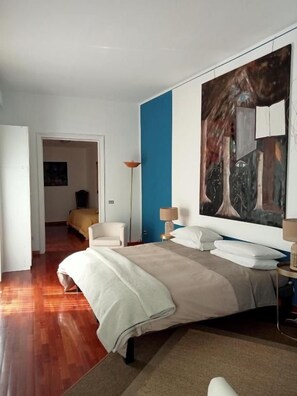 Une chambre à coucher avec un lit, une table de chevet, une lampe et un grand tableau abstrait accroché au mur.