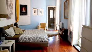 A bedroom with a bed, bedside table, chair, and artwork on the wall. - Altera Domus (Naples)