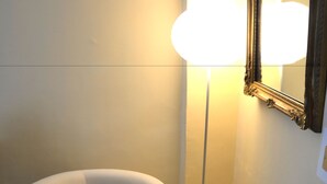 A corner of a room with a white armchair, a floor lamp, and a patterned rug. - Altera Domus (Naples)