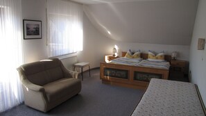 A bedroom with a single bed, a chair, a small table, and a radiator. - Pension Restaurant Schnorbus (Hallenberg)