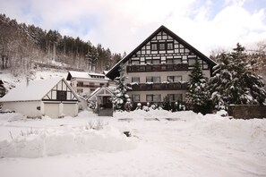 A traditional chalet-style building with a steeply pitched roof, multiple balconies, and a snow-covered landscape. - Pension Restaurant Schnorbus (Hallenberg)