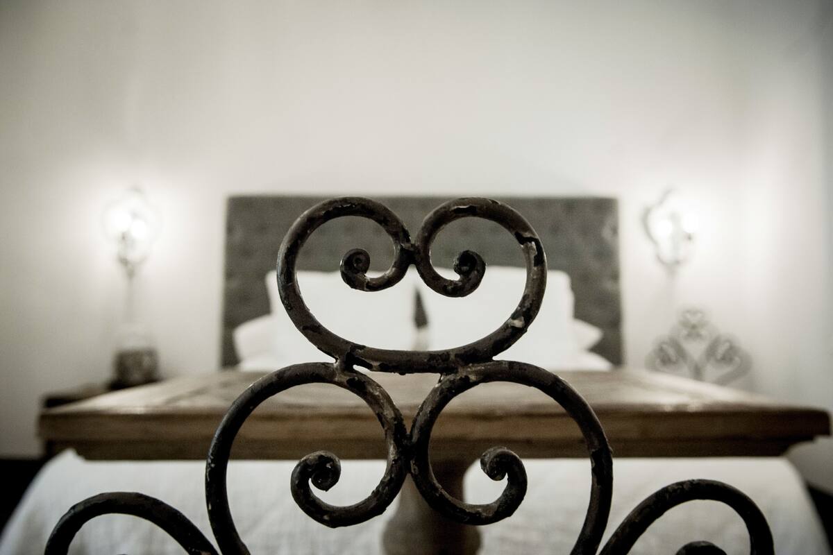 A bed with a wooden headboard and a metal decorative frame in the foreground.