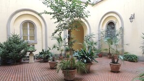 A courtyard with potted plants and a tiled floor. - Angelina B&B Dimora Contemporanea (Rome)