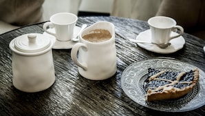 A table with a coffee pot, two cups, a spoon, and a slice of pie on a patterned plate. - Angelina B&B Dimora Contemporanea (Rome)