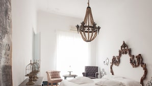A bedroom with a large bed, two chairs, a small table, a chandelier, and a decorative mirror. - Angelina B&B Dimora Contemporanea (Rome)