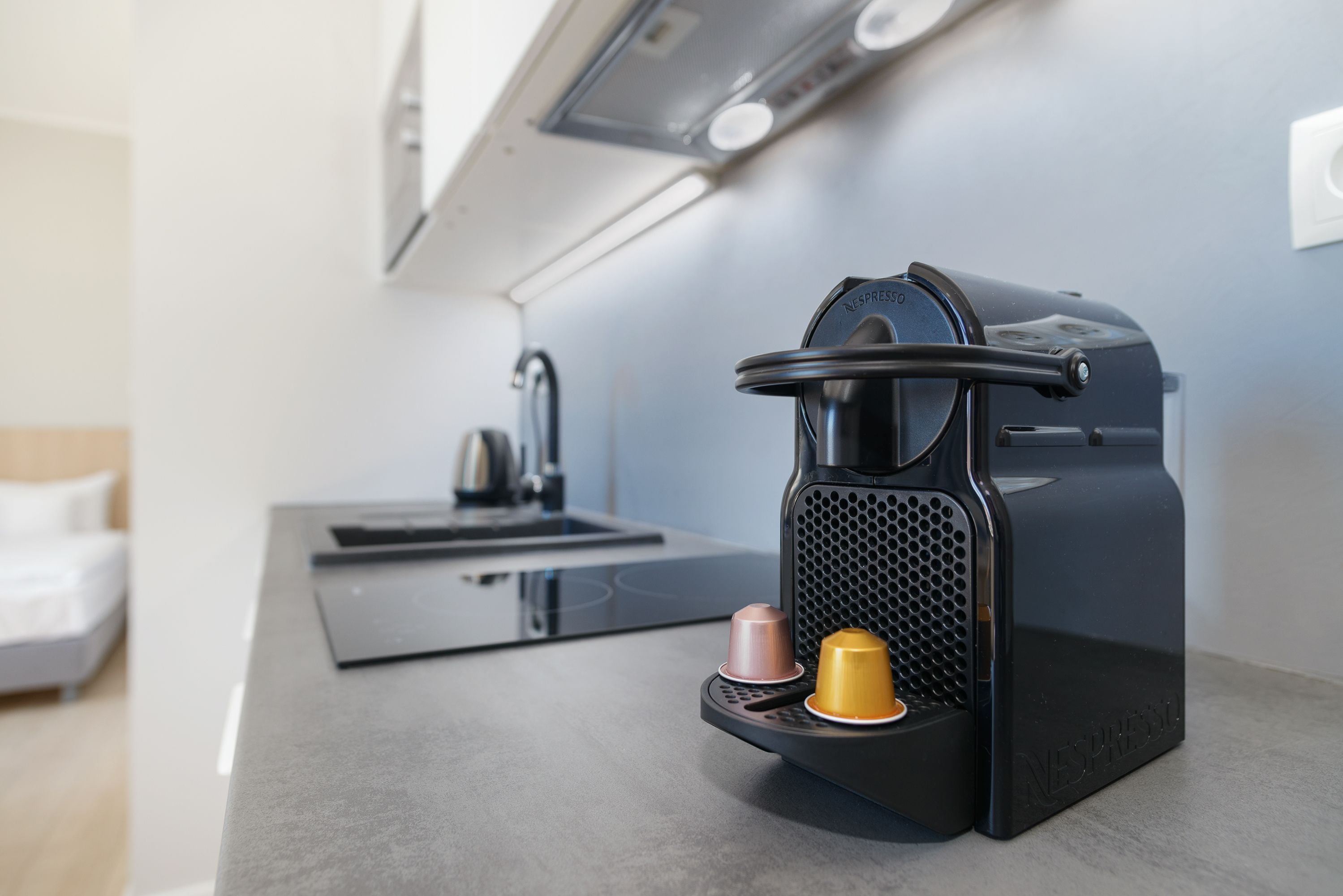A modern kitchen with a coffee machine, a sink, and a countertop.