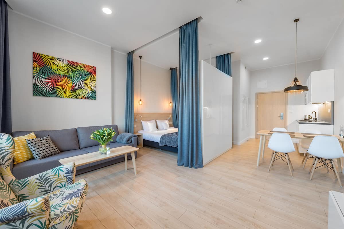 Un salon moderne avec un canapé, une table basse et un lit doté d’une tête de lit. On y trouve également un coin repas avec une table et des chaises.