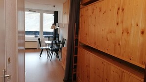 Huoneessa on puinen vaatekaappi, ruokapöytä tuoleineen ja ikkuna, josta on näkymä.