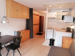 A compact kitchen with a dining area, wooden cabinets, a small refrigerator, and a coffee machine. - Southwest studio in Val-Claret, near shops (Tignes)