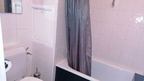 Kylpyhuone, jossa on wc, kylpyamme ja suihkuverho.