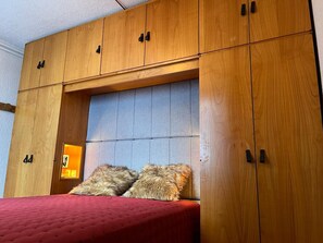 A bedroom with a wooden wardrobe, a bed with a red bedspread, and two fluffy pillows. - 41m² South Apartment with Wifi near slopes in Tignes (Tignes)
