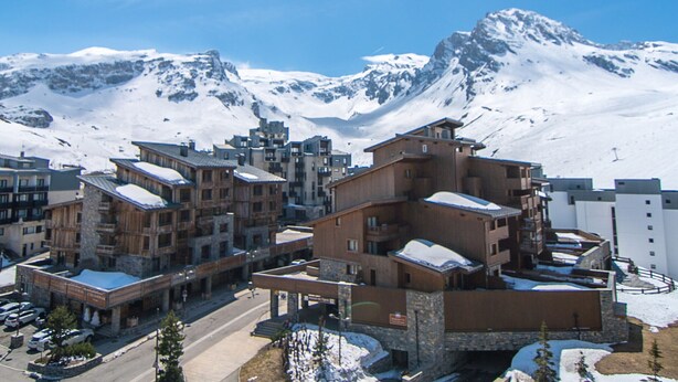 A snow-covered mountain town with multi-story buildings, a central plaza, and a ski lift in the background. - Southwest studio in Tignes, near slopes, 27 m² (Tignes)