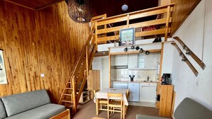 A cozy cabin with a loft bedroom, a kitchenette, and a living area with two sofas and a coffee table. - 2-room south-facing, ski-in/ski-out, balcony, TV, linen included (Tignes)