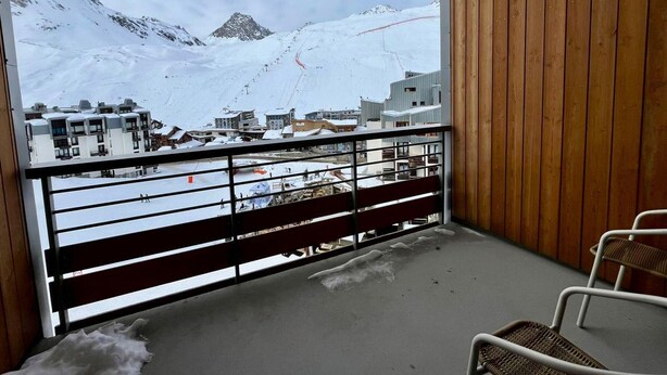 A balcony with a view of a snowy mountain landscape, wooden paneling, and a metal railing. - 2-room south-facing, ski-in/ski-out, balcony, TV, linen included (Tignes)