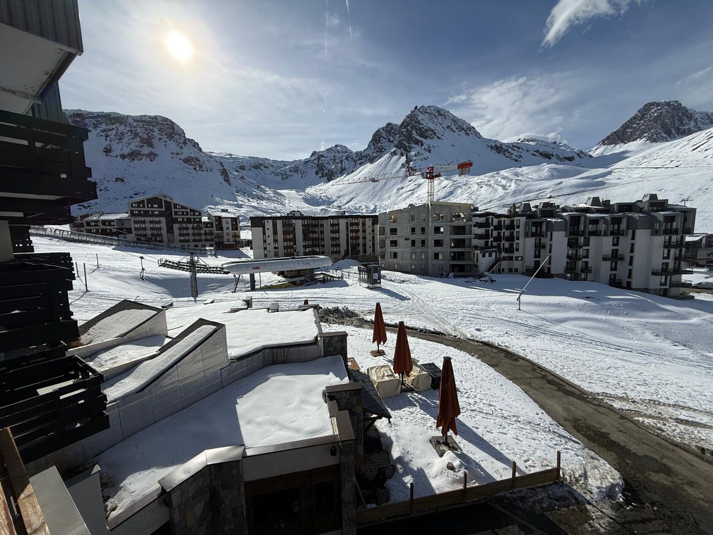 Une station de montagne enneigée, composée de plusieurs bâtiments, dont un hôtel doté de balcons, et où l'on peut apercevoir un télésiège.