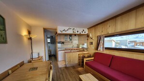A compact living space with a dining area, kitchenette, and a red sofa.