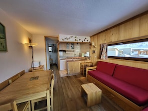 Ein kompakter Wohnraum mit Essbereich, einer Küchenzeile und einem roten Sofa.
