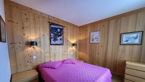 A wooden-paneled room with a bed, bedside lamps, and a dresser.