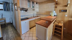 A compact kitchen with wooden cabinets, a built-in oven, and a wooden countertop.