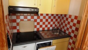 Eine kleine Küche mit Kühlschrank, Herd und Spüle.