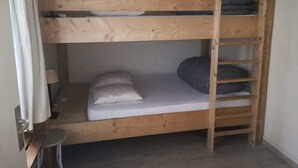 Ein Stockbett mit einer Leiter, einem kleinen Tisch und einer Lampe.