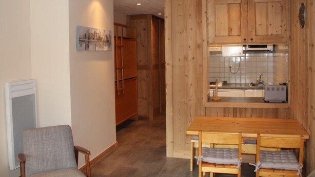 Une cuisine compacte avec des meubles en bois, une table à manger avec des chaises et une petite fenêtre au-dessus de l’évier.