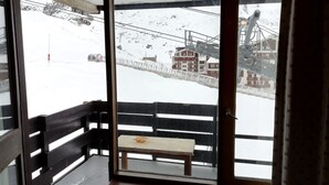 Une vue enneigée sur l’extérieur, prise depuis une fenêtre, avec un banc à l’intérieur.