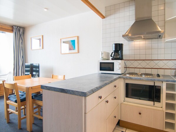 A compact kitchen with a dining area, featuring a microwave, stove, and a coffee maker.
