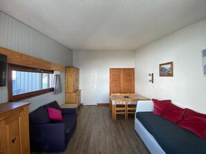Ein gemütlicher Raum mit einem Holzschrank, einer Sitzecke, einem Esstisch mit Stühlen und einem Bett.
