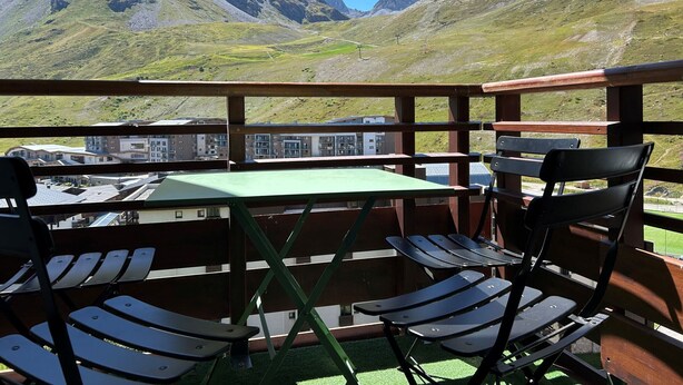A balcony with a table and chairs overlooking a mountainous landscape. - Renovated 3-room apartment, south/west facing, near shops (Tignes)