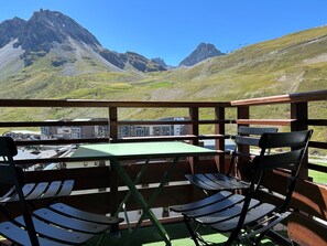 A balcony with a table and chairs overlooking a mountainous landscape.