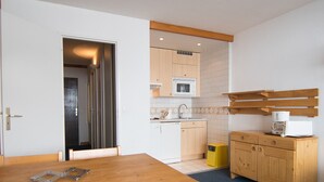 Kompakti keittiö, jossa on puiset kaapit, mikroaaltouuni ja kahvinkeitin työtasolla.