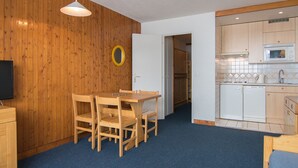 Pieni, käytännöllinen keittiö, jossa on puukaapit, mikroaaltouuni ja pesuallas.