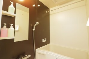 A bathroom with a bathtub, a mirror, and shelves with toiletries. - Modern Apartment Osaka Dome Mae (Osaka)