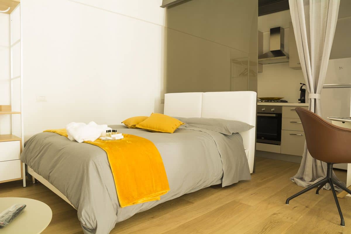 A modern hotel room with a bed, a desk, and a chair.