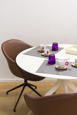 Una mesa redonda con superficie blanca y una silla marrón.
