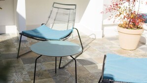 Un espace patio avec une chaise en métal et une petite table, tous deux dotés de coussins bleus.
