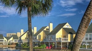 A waterfront property with multiple houses, a grassy area, and a body of water. - 🏝️🏖️Sandpiper Cove, Private Beach Access Overlooks Heated Pool (Destin)