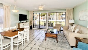 A living room with a dining area, a sofa, a coffee table, and a TV. - 🏝️🏖️Sandpiper Cove, Private Beach Access Overlooks Heated Pool (Destin)